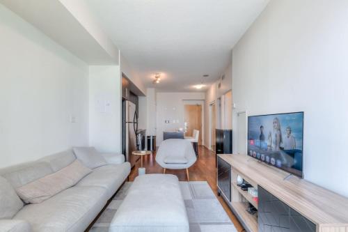 a living room with a white couch and a tv at 1BR plus Den Condo with Balcony in Heart of Toronto in Toronto