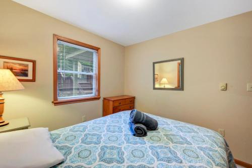 a bedroom with a bed with a blue comforter and a window at beautiful lakefront lodge in Lake Harmony