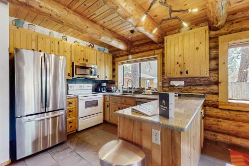 a kitchen with wooden cabinets and a stainless steel refrigerator at Sunriver Log Cabin in Bend