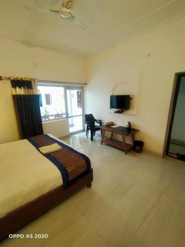 a bedroom with a bed and a desk and a television at Chelsea Palace Khajuraho in Khajurāho