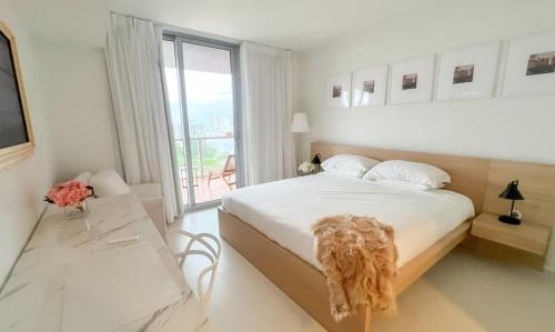 a white bedroom with a large bed and a window at 1br BeachWalk Ocean View in Hallandale Beach