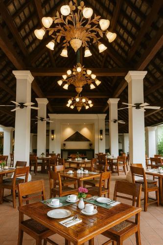 a dining room with tables and chairs and a chandelier at The Grand Luang Prabang, Affiliated by Meliá in Luang Prabang