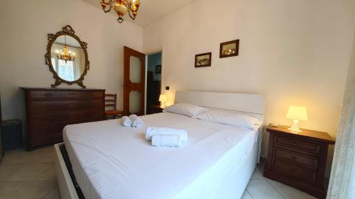 een slaapkamer met een wit bed met twee handdoeken erop bij Hostdomus - La casina di Monica in Loano