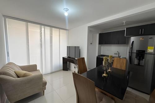 a kitchen with a table and a couch and a refrigerator at Urb. natura in Cúcuta