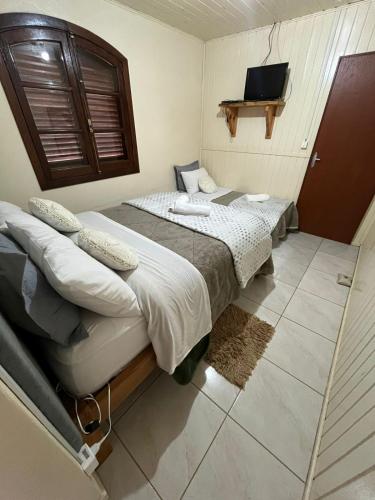 two beds in a room with a tv on the wall at pousada vó biloca in Urubici