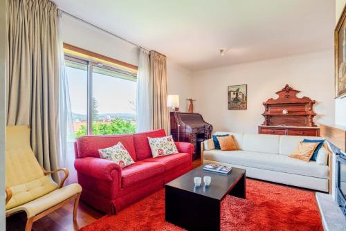 a living room with a red couch and a red chair at Villa Luzia by Portugal Active in Viana do Castelo