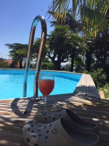 un verre de vin et une paire de chaussures au bord d'une piscine dans l'établissement VILLA SAINT VINCENT, à Agen