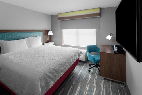 a hotel room with a bed and a desk and a television at Hampton Inn & Suites By Hilton Long Island Farmingdale in Farmingdale