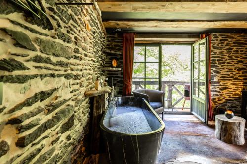 a bath tub in a room with a stone wall at Les Cabanes de Rensiwez in Mabompré