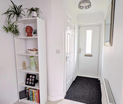 a hallway with white shelves and a white door at Lanhydrock View in Bodmin