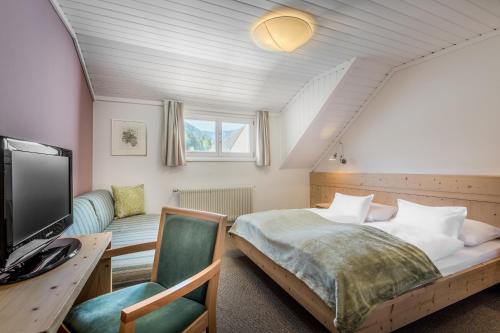 a bedroom with a bed and a tv and a couch at Gasthof Traube in San Lorenzo di Sebato
