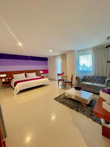 a large bedroom with a bed and a couch at Hotel Atrium Plaza in Barranquilla