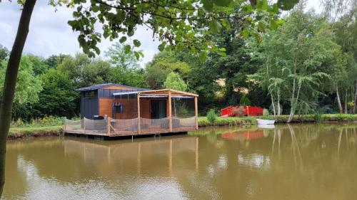 a small house sitting on top of a body of water at Chalet sur l'eau dans un cadre idyllique in Nesmy