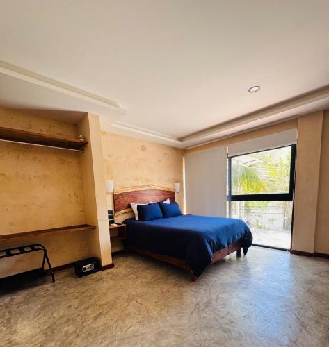 a bedroom with a blue bed and a large window at Kauil Tulum in Tulum