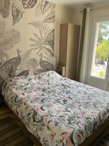 Un dormitorio con una cama con una colcha floral. en La Maison du Bonheur, en Thaims