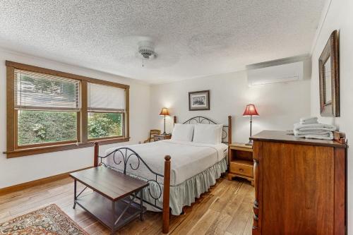 a bedroom with a bed and a table and two windows at QKA View in Penn Yan