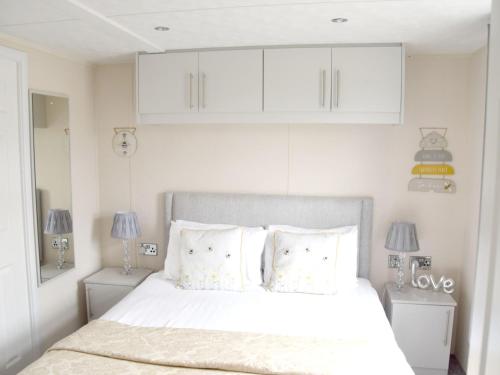 a white bedroom with a bed with white cabinets at Elm 34 Hot Tub in Garton