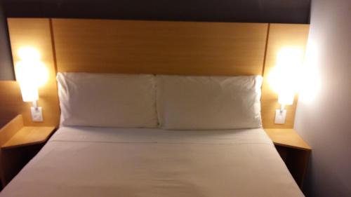 a bedroom with a bed with two lights on it at ibis Juiz de Fora in Juiz de Fora