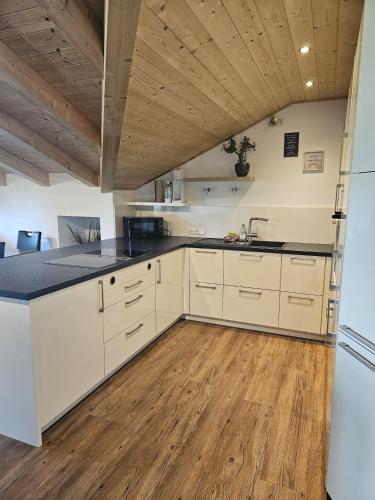 a kitchen with white cabinets and a wooden ceiling at RoSa Seeblick in Steingädele