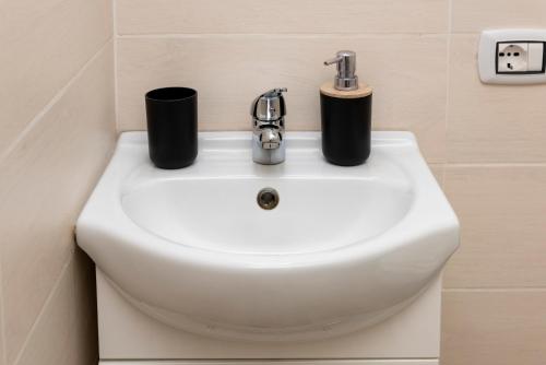 a sink in a bathroom with two cups on it at SASSARI-CENTRO Elegante Appartamento con WiFi e Netflix in Sassari