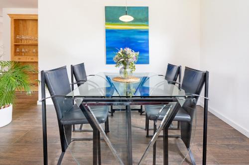 een glazen eettafel met stoelen en een vaas met bloemen bij Achtern Hoff in Gnissau