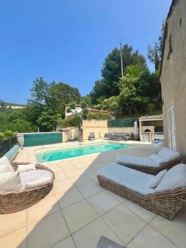 - une piscine avec 2 chaises en osier à côté de la piscine dans l'établissement Sur les hauteurs de Nice, belle villa idéale en famille ou entre amis, à Colomars