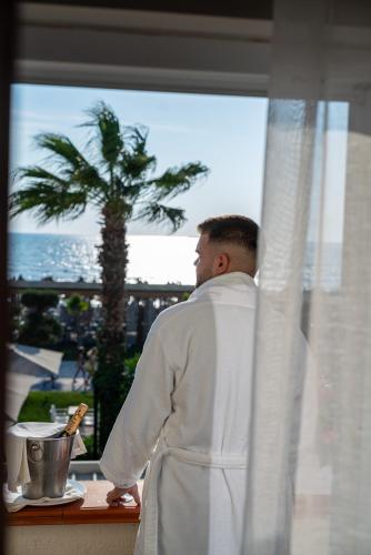 a man in a robe looking out of a window at Vila Lasko Hotel in Golem