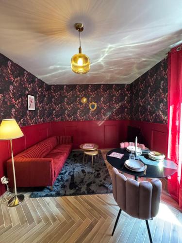 a living room with a red couch and a table at RED SPARROW -T2 avec jacuzzi in Châteauroux
