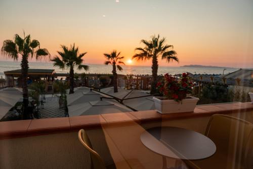 a balcony with tables and palm trees and the ocean at Vila Lasko Hotel in Golem