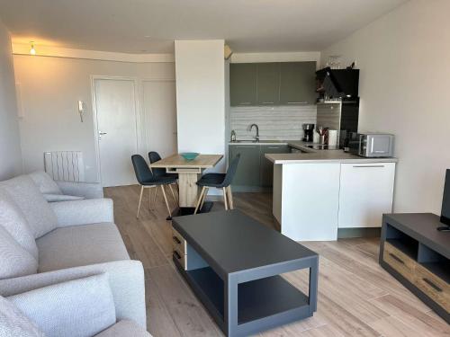Una sala de estar y una cocina con un sofá y una mesa. en 530 - Appartement T3, à Erquy, avec pleine vue mer, en Erquy