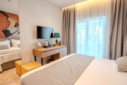 a bedroom with a bed and a desk with a television at Vila Lasko Hotel in Golem