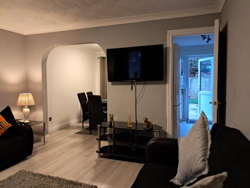 a living room with a couch and a tv on the wall at FANTASTIC COZY 3bed Hse London ExCEL Free Parking WIFI Sleeps 6 in London