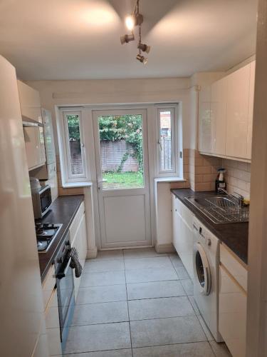 a kitchen with a washer and sink and a door at FANTASTIC COZY 3bed Hse London ExCEL Free Parking WIFI Sleeps 6 in London