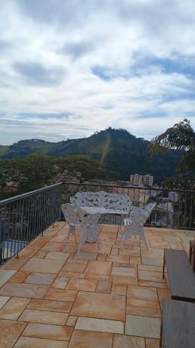 a table and benches on a balcony with a view at Casa com piscina para até 6 pessoas com duas camas de casal e sofá-cama casal in Serra Negra