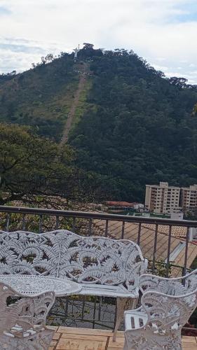a white bench sitting on a balcony with a mountain at Casa com piscina para até 6 pessoas com duas camas de casal e sofá-cama casal in Serra Negra