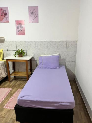 a bed with purple sheets in a room with a table at Suíte Freitas Piri in Pirenópolis