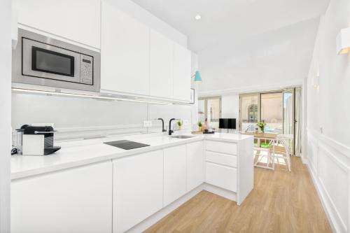 a white kitchen with white cabinets and a microwave at Solaga - Ático Sebastián Souvirón in Málaga
