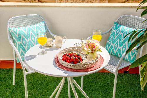 a white table with a bowl of fruit and two chairs at Solaga - Ático Sebastián Souvirón in Málaga