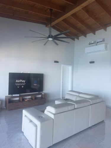 a living room with two stools and a flat screen tv at Heart of Poms Villa in Punta Blanca