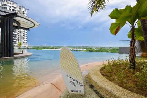 a surfboard sitting in the sand next to the water at Macrolink Medini Theme Suite by Nest Home - Near Legoland in Iskandar Puteri