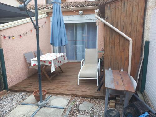 un patio avec un parasol, une table et des chaises dans l'établissement Le CENTAURE Proche Centre Naturiste, au Cap d'Agde