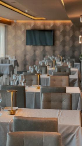 a dining room with tables and chairs and a screen at Lisotel - Hotel & Spa in Leiria