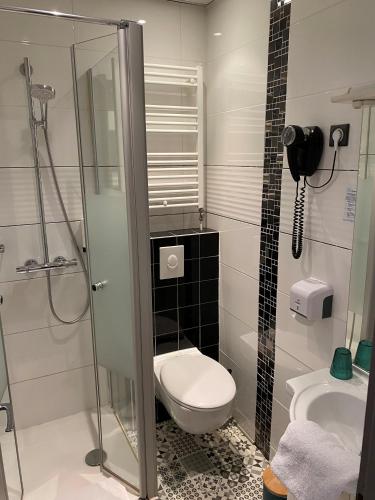 a bathroom with a toilet and a glass shower at Hôtel Beausoleil in Montélimar