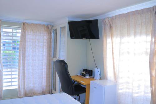 a bedroom with a desk with a chair and a television at Elite Stay Guest House in Rustenburg