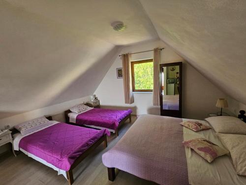 two beds in a attic room with purple sheets at Guesthouse Loncar in Plitvička Jezera