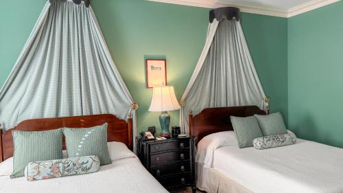 two beds in a bedroom with blue walls and curtains at John Rutledge House Inn in Charleston