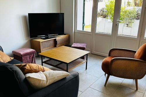 un salon avec une télévision, une table et des chaises dans l'établissement Very spacious cocoon with garden near the sea, au Pouliguen
