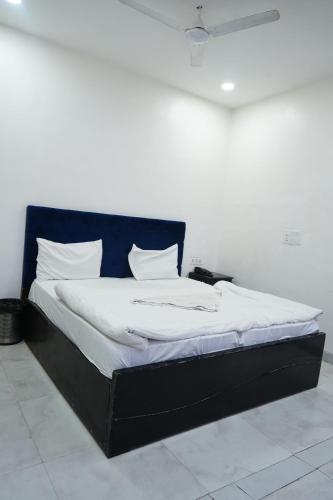 ファリーダーバードにあるMayur Hotel Near IMT College, Faridabadの黒枠のベッド、白いシーツ、枕