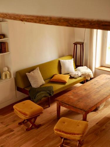 ein Wohnzimmer mit einer grünen Couch und einem Tisch in der Unterkunft Ferme des Millonets - grand gîte in Vienne-en-Arthies