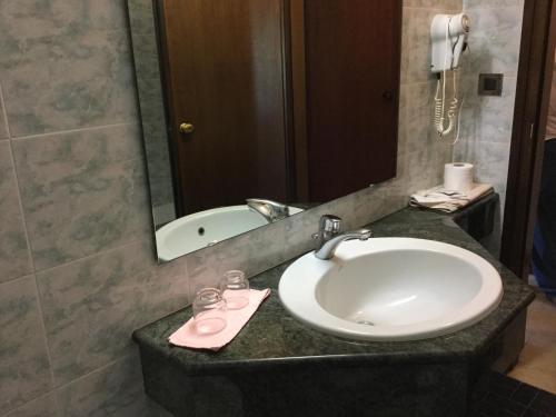 a bathroom with a sink and a mirror and a tub at Hotel Terme Vulcania in Montegrotto Terme